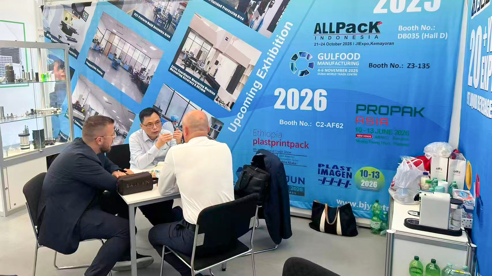 Инженерите на Foshan Baijinyi Precise Technology обясняват на посетителите персонализирането на PET матрици и решенията за обратно инженерство на щанд C5-640, drinktec 2025.