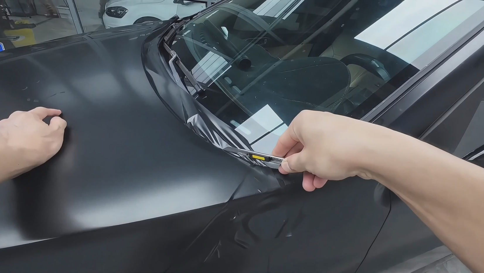 Instalador profesional recortando manualmente la película protectora de pintura en un panel de vehículo durante la instalación de la película protectora de pintura cortada a mano.