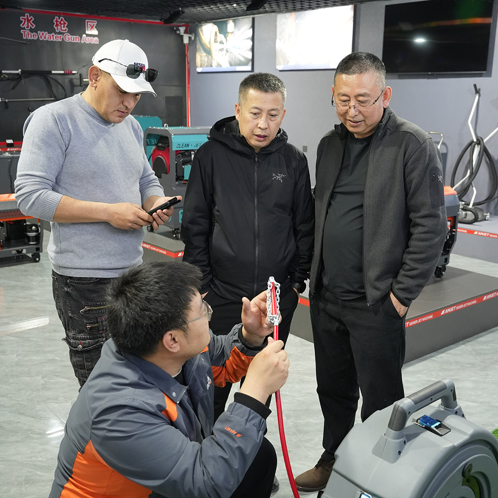 International plumbers visiting AMJET factory discussing sewer jetter machine operation.jpg