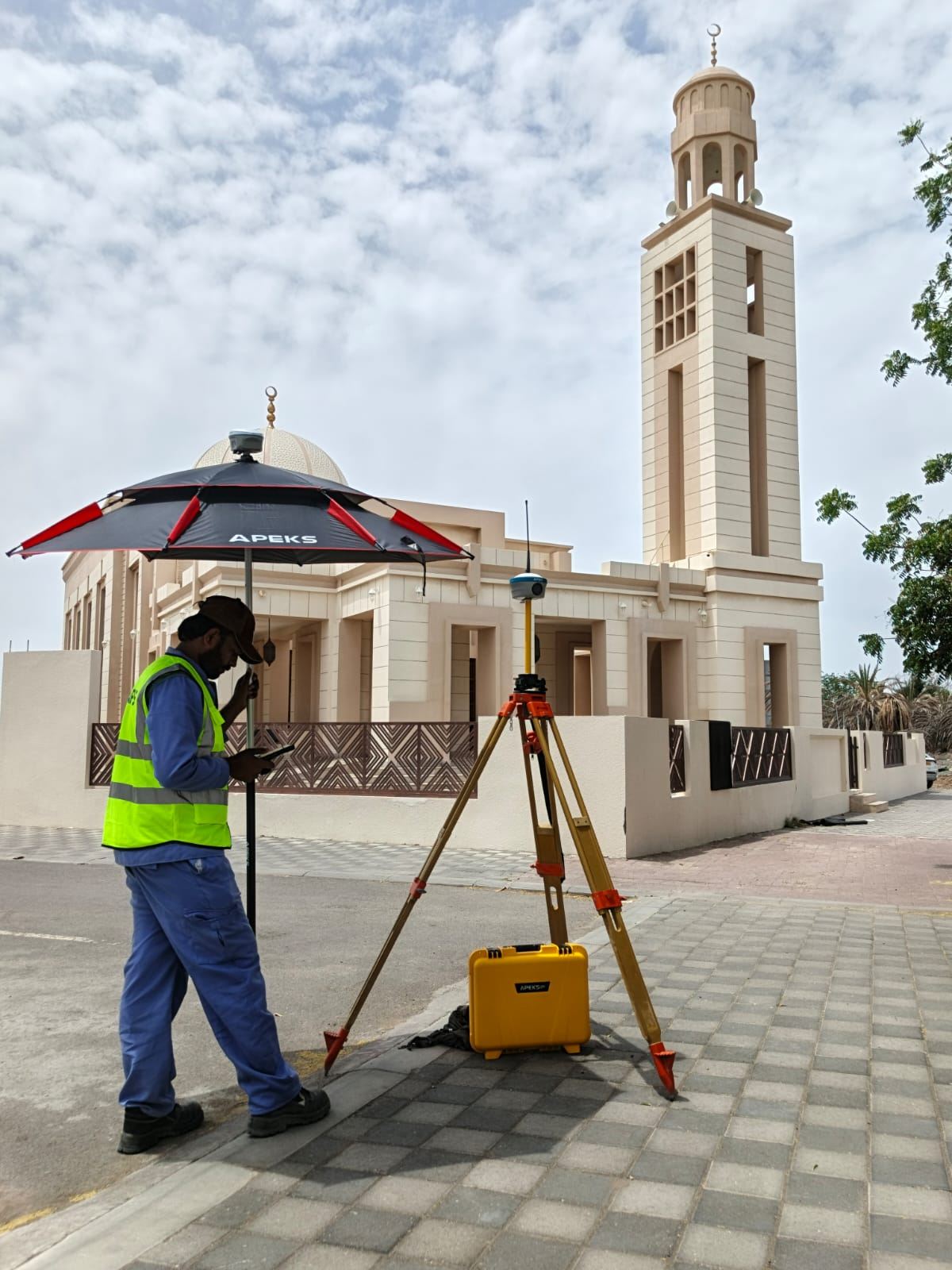 Surveyor using APEKS AP40 Laser+ RTK receiver for pile foundation stakeout on Oman utility-scale solar project