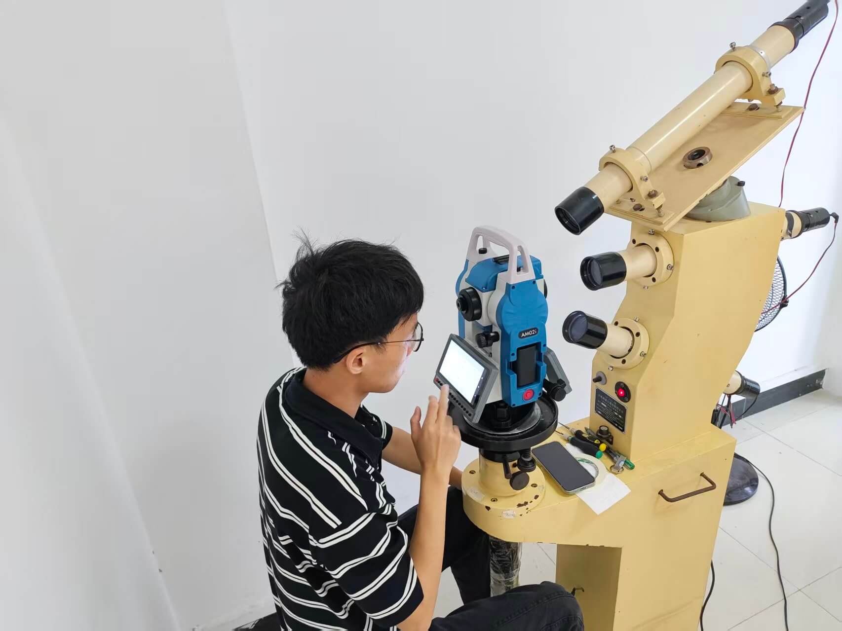 Engineer conducting multi-collimator optical calibration and accuracy testing on APEKS AM02i total station