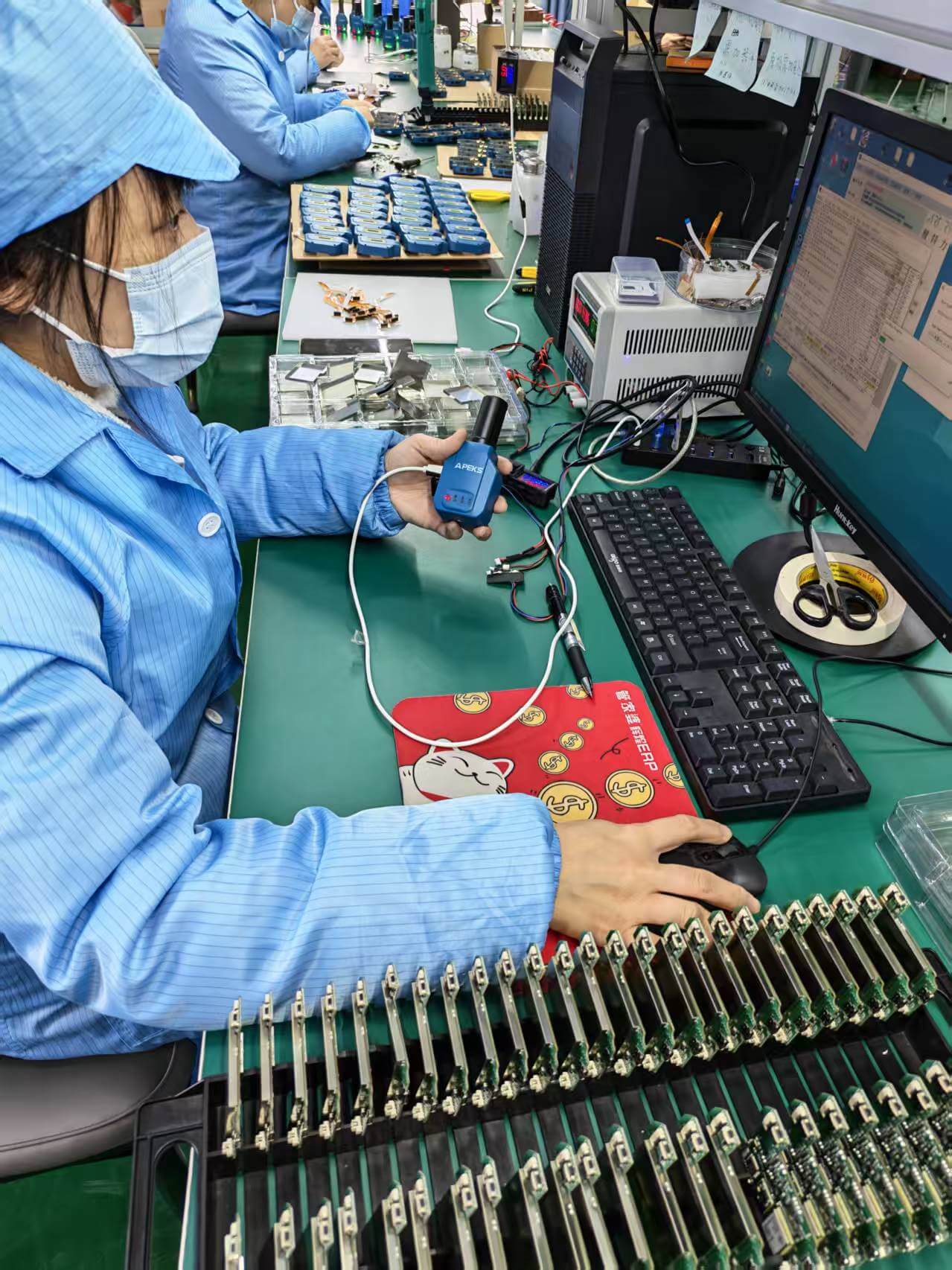 Technician conducting firmware flashing and diagnostic testing on APEKS APS1 handheld GNSS receiver