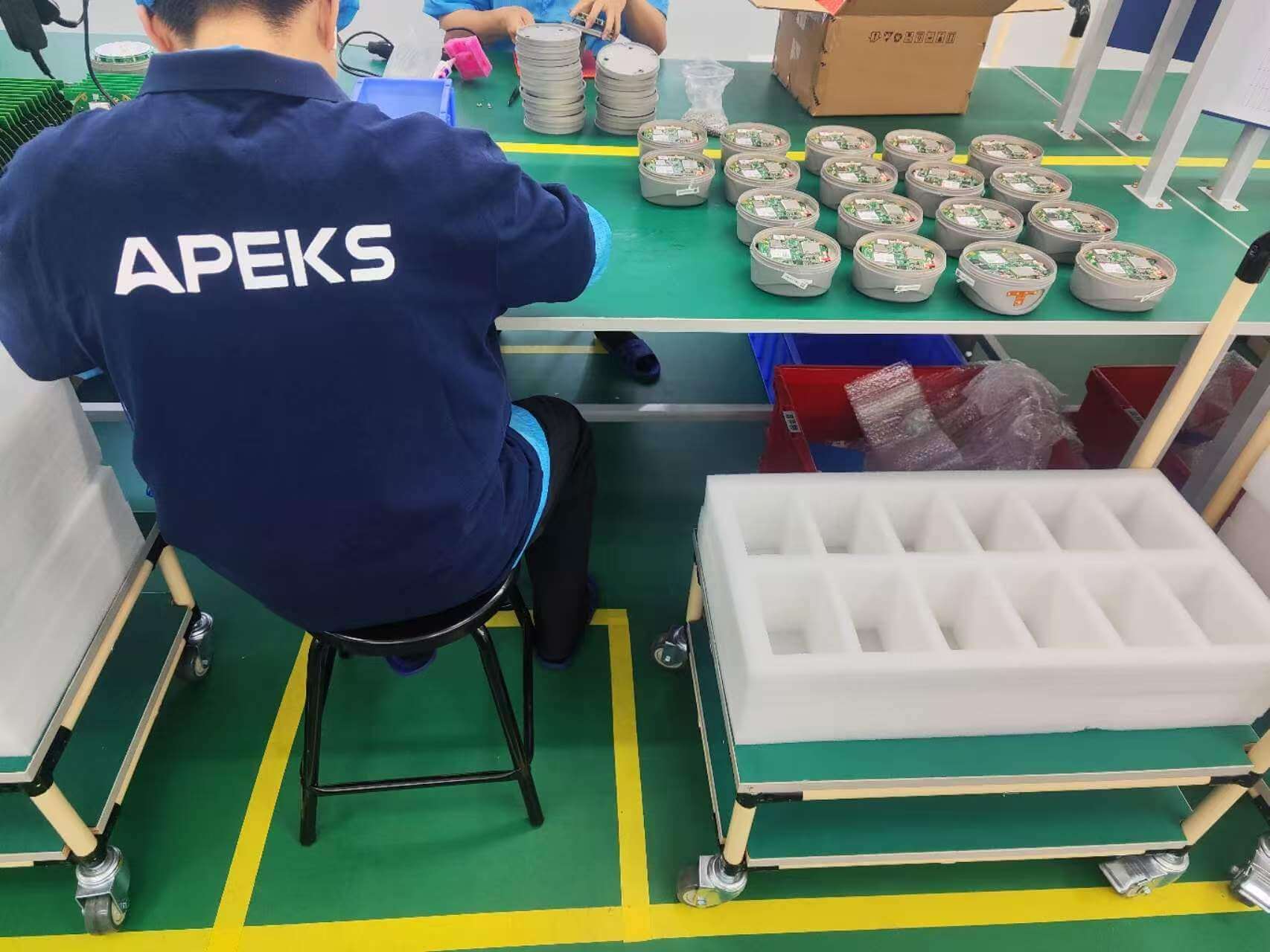 Technician assembling APEKS GNSS RTK receivers on the factory production line workbench