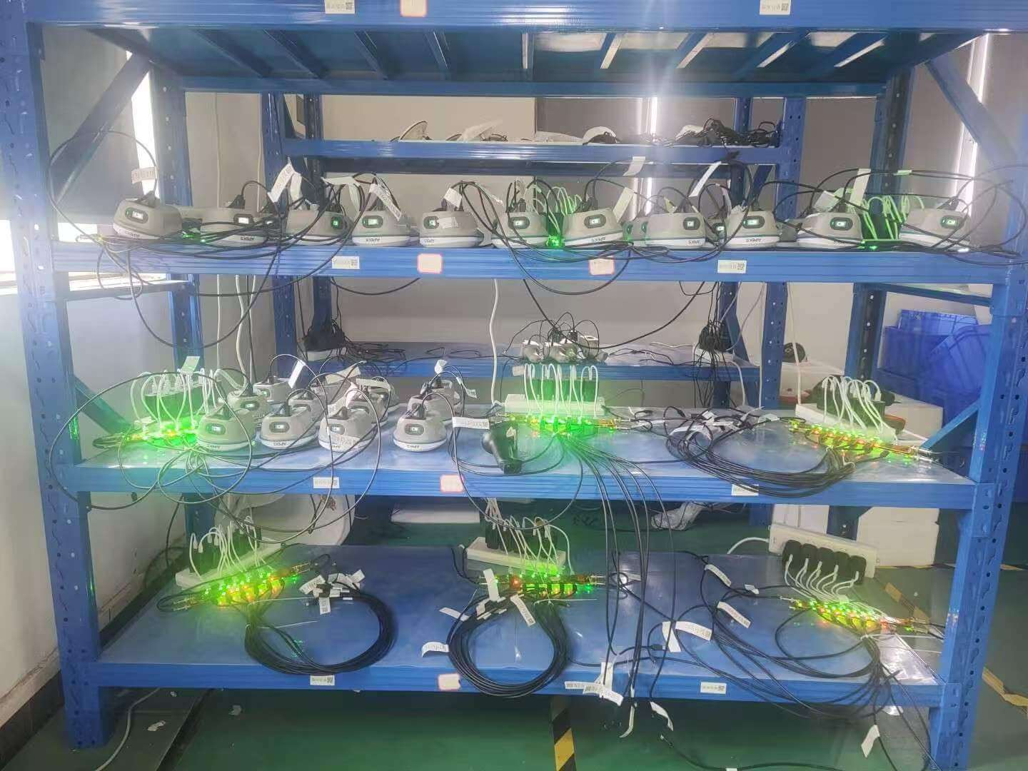Multi-tier factory testing rack conducting continuous power, signal, and aging diagnostics on APEKS GNSS receivers
