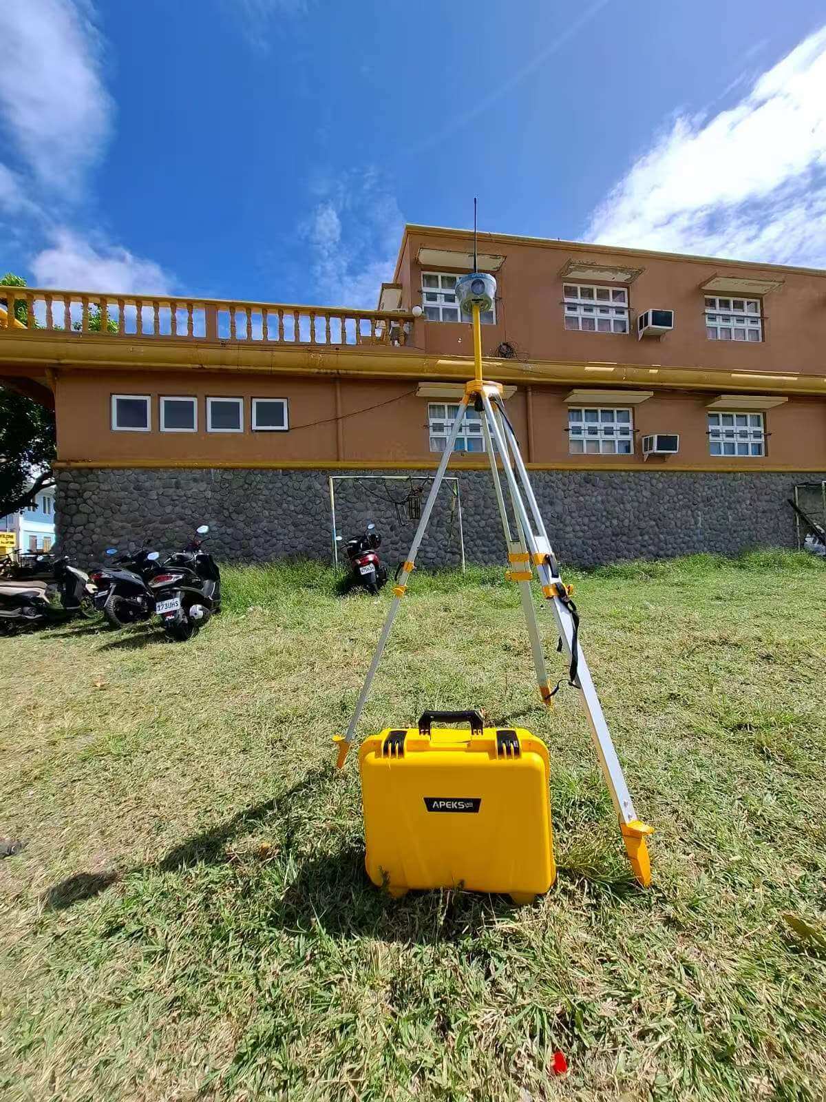 APEKS MAX5 RTK base station mounted on an aluminum survey tripod with a heavy-duty yellow field carry case