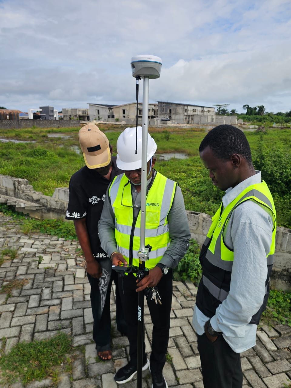 Close-up of engineers operating ApekSurv field software on an APEKS handheld controller mounted on an RTK rover pole in Nigeria