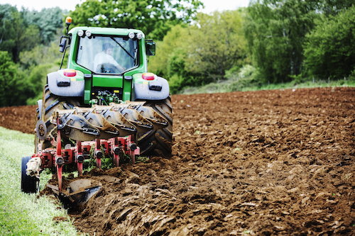 a-tractor-ploughing-the-soil-in-a-field-harrowing-NKEHAPY