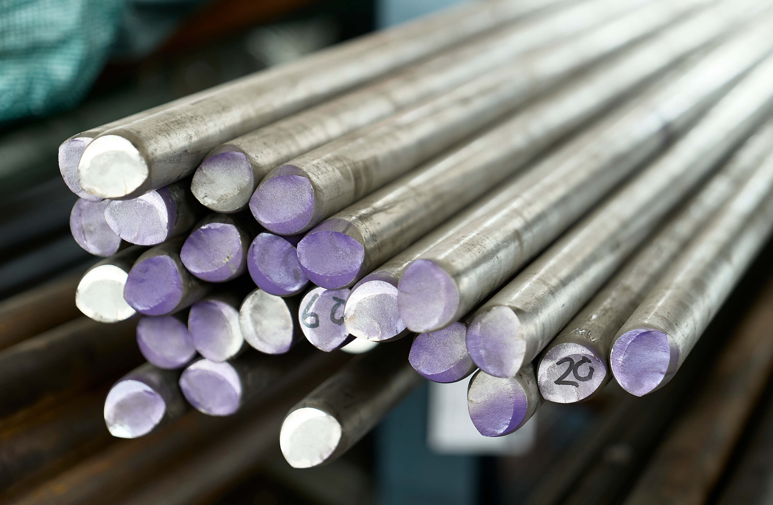  Close-up of 316L stainless steel bars with purple color-coded ends in a manufacturing warehouse.