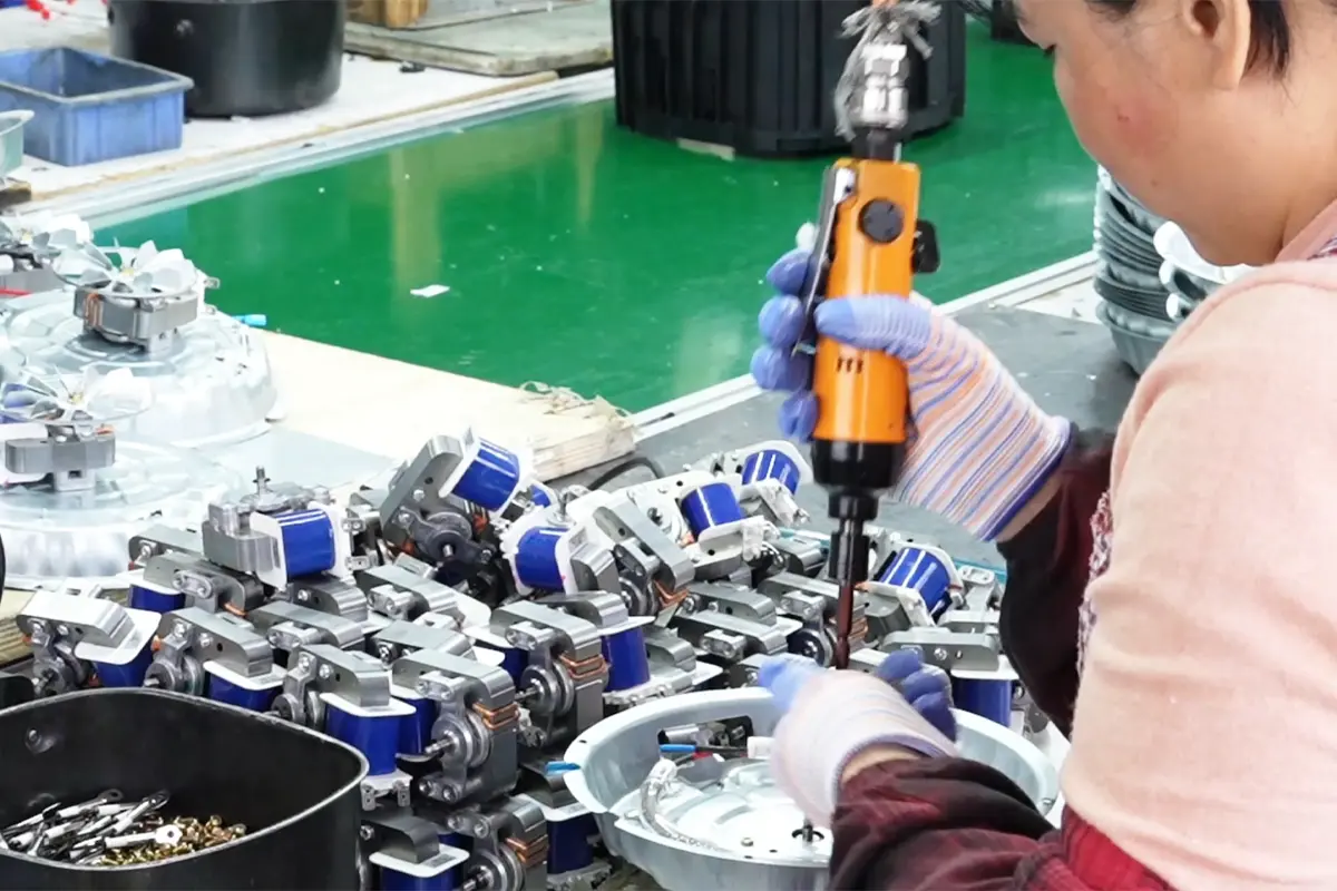 Worker fastening air fryer heating and internal components during assembly