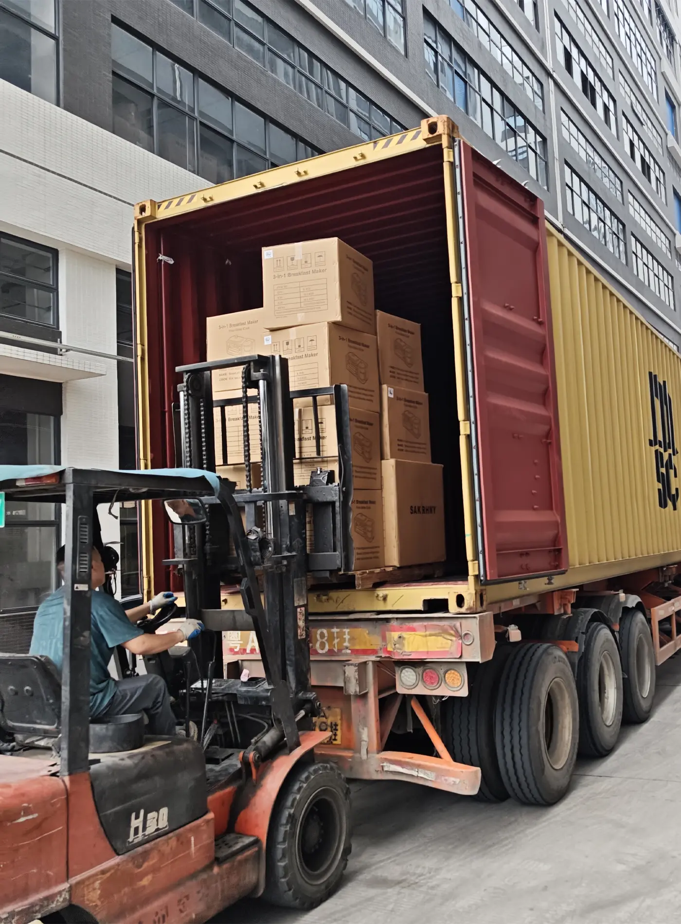 Forklift placing packed kitchen appliance cartons into a container during loading