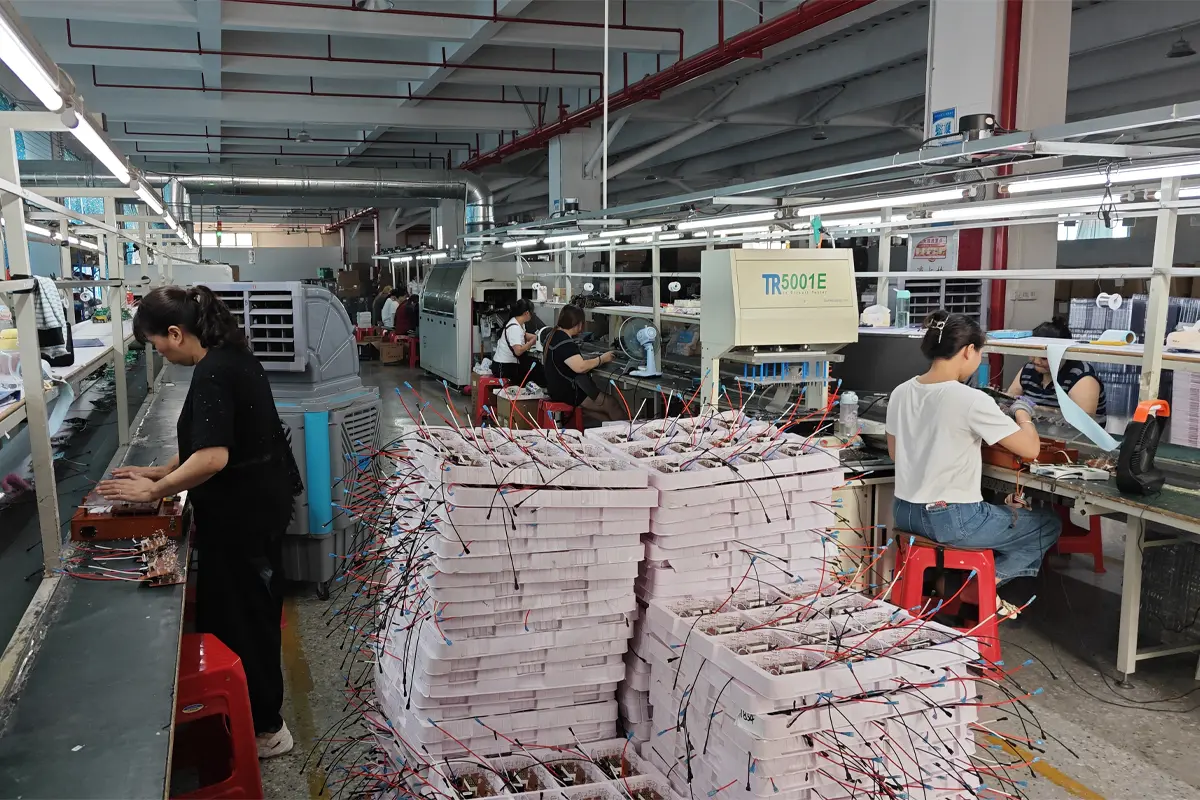 APEXDURA PCB soldering workshop with circuit board trays, workers and equipment