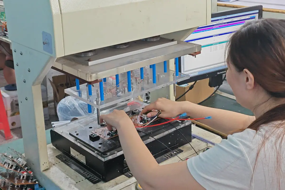 Operator placing a kitchen appliance circuit board into a fixture in APEXDURA PCB workshop