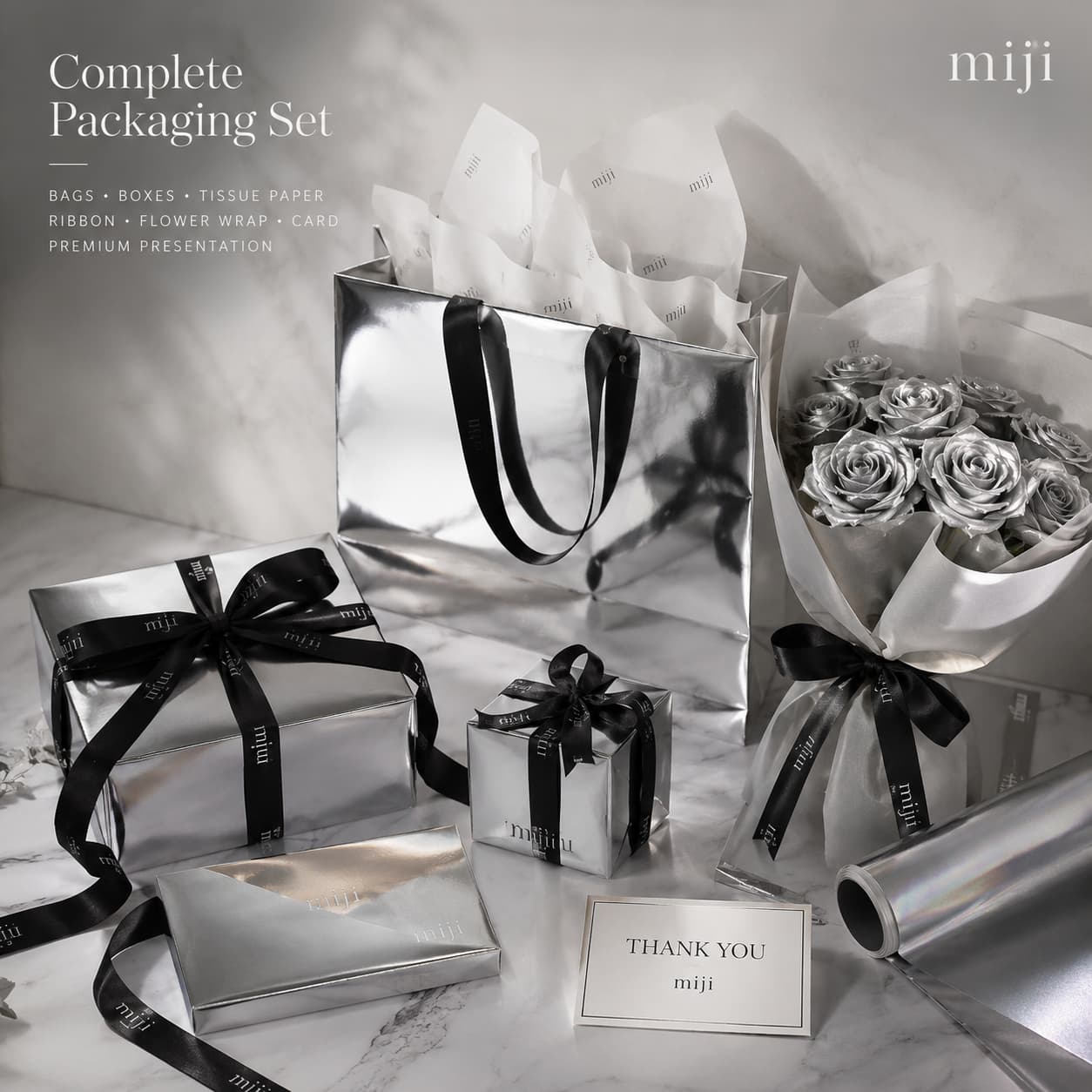 A coordinated silver and white premium packaging set with metallic paper bags, gift boxes, tissue, ribbon and cards.